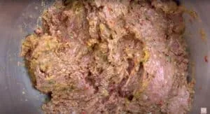 Raw meat mixture with herbs and spices in a bowl, ready for cooking or baking.